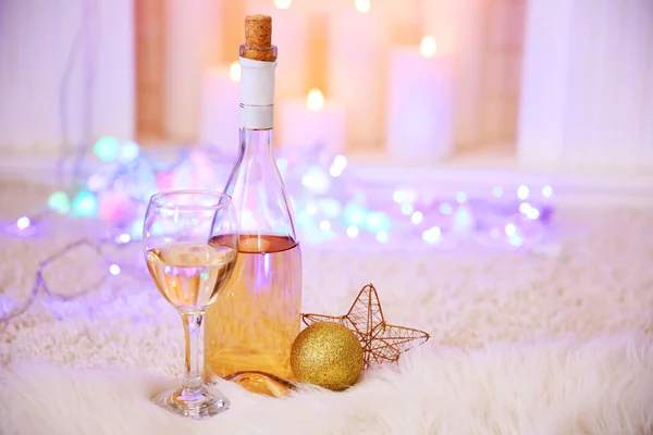 Bottiglia e bicchiere di vino con decorazioni natalizie contro le luci colorate bokeh sfondo — Foto Stock