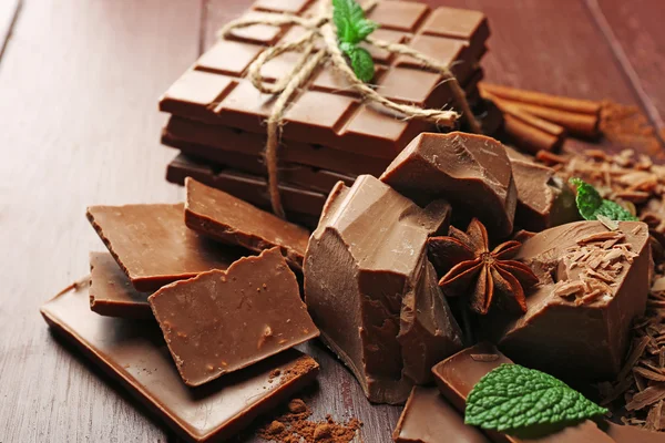 Variety of chocolate pieces, coffee grains and cocoa powder on wooden background — Stock Photo, Image