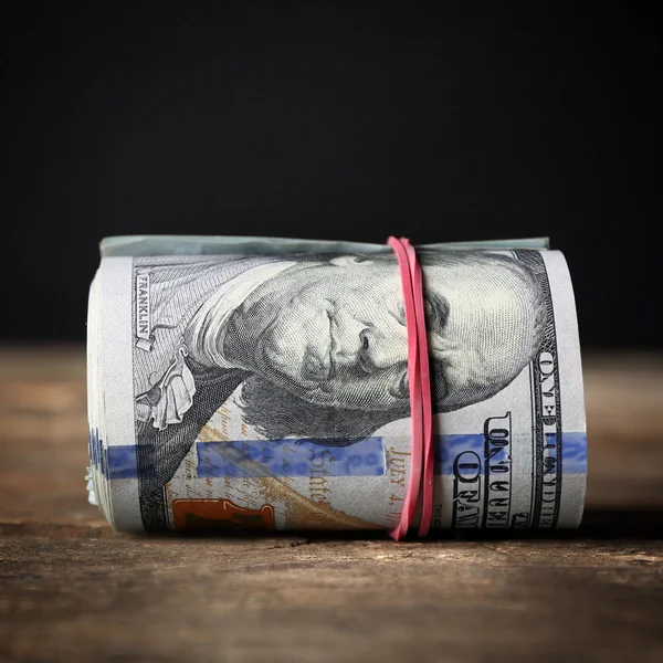 Dollar rollen auf Holztisch vor dunklem Hintergrund — Stockfoto