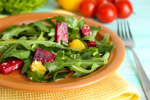 Leckerer Salat mit Rucolablättern im Teller auf Holztisch, Nahaufnahme — Stockfoto
