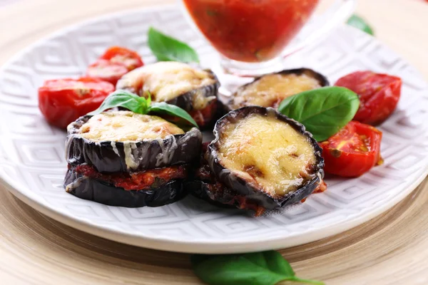 Dish of eggplant with cherry tomatoes and cheese in white plate on wooden table, closeup — Stock Photo, Image