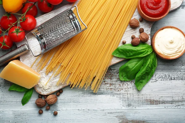 Makarna spagetti domates, peynir ve renk ahşap arka plan üzerinde fesleğen ile — Stok fotoğraf