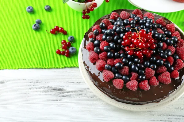 Köstlicher Schokoladenkuchen mit Sommerbeeren auf Holztisch mit grüner Serviette, Nahaufnahme — Stockfoto