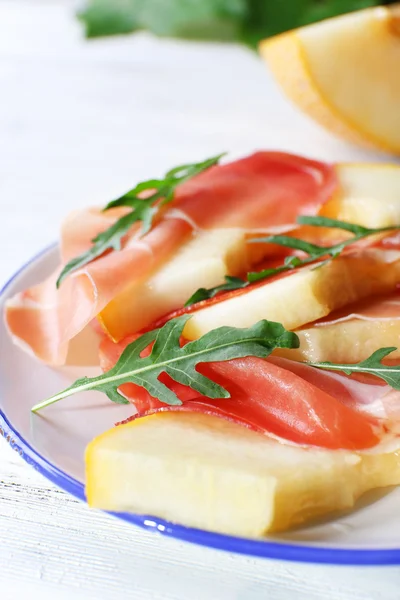 Melon with prosciutto of Parma ham on wooden table, closeup — Stock Photo, Image