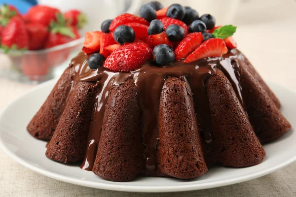 Вкусный шоколадный кекс с глазурью и ягодами на столе вблизи — стоковое фото