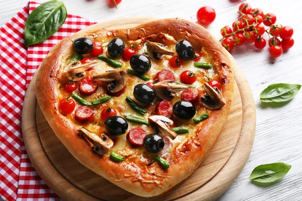 Pizza gustosa a forma di cuore e tovagliolo di cotone rosso su fondo di legno — Foto Stock