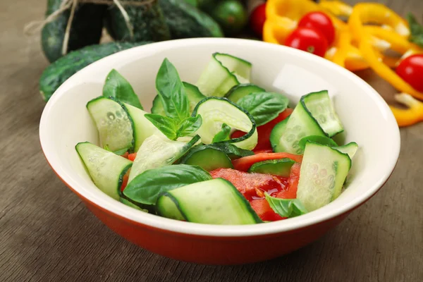 Vegetable salad with cucumbers on wooden background — Stock Photo, Image