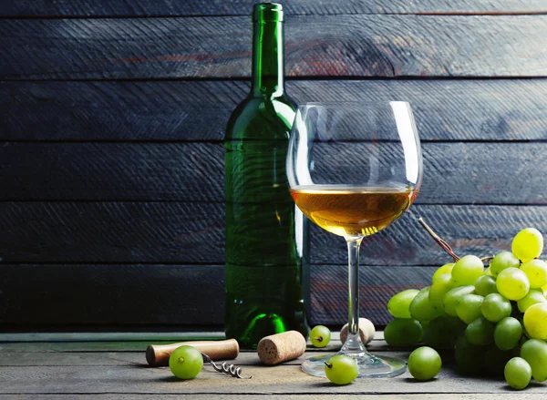 Flasche und Glas Wein mit Trauben auf Holzgrund — Stockfoto