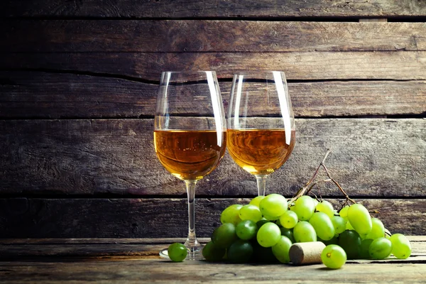 Skleničky vína z hroznů na dřevěné pozadí — Stock fotografie
