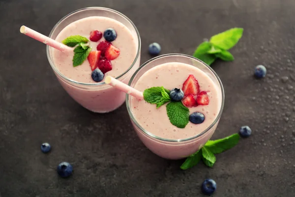 Yogurt gustoso decorato con bacche e menta su sfondo grigio — Foto Stock