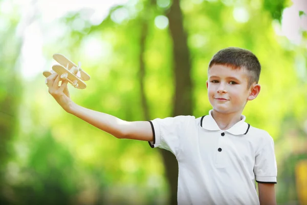 Little boy plays with wooden plane — Stock Photo, Image