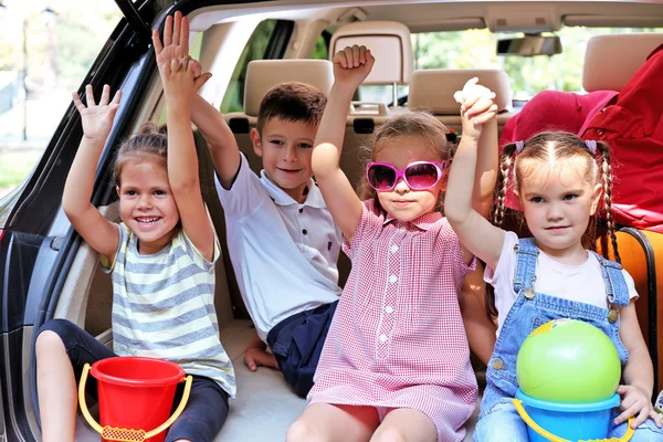 Meisjes en jongen zitten op de auto kofferbak — Stockfoto
