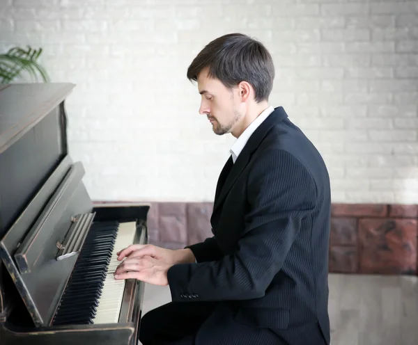 Hombre de traje negro toca el piano — Foto de Stock