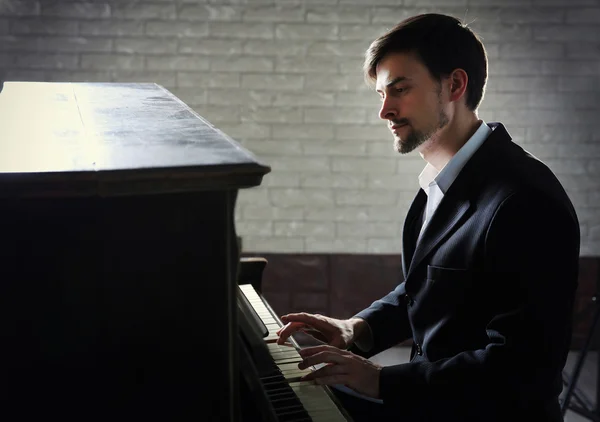 Homem de terno preto toca piano — Fotografia de Stock