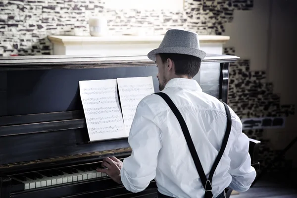Przystojny młody mężczyzna w kapeluszu Dokonywanie muzyki fortepianowej, widok z tyłu — Zdjęcie stockowe