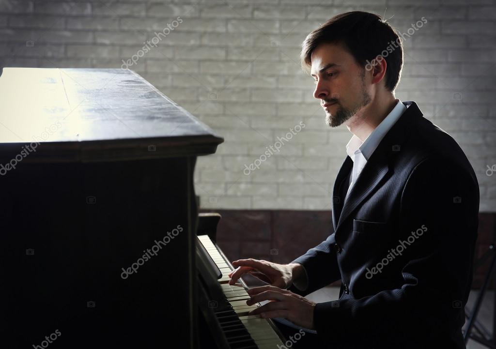 man in black suit plays piano — Stock Photo © belchonock #87640576