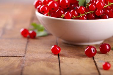 Ahşap masa üzerinde kase taze kırmızı kuş üzümü yakın çekim