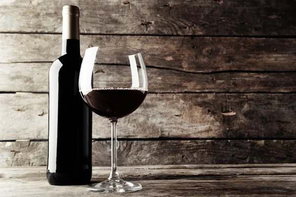 Bouteille de vin rouge et un verre sur table en bois, noir et blanc rétro stylisation — Photo