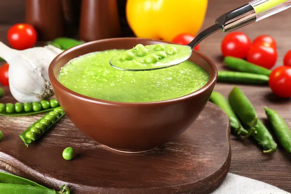 Tasty peas soup and vegetables on table close up — Stock Photo, Image