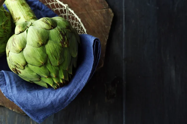 Artichauts dans le panier sur fond en bois de couleur — Photo