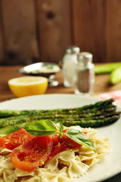 Asperges rôties et pâtes savoureuses avec légumes sur fond de table en bois — Photo