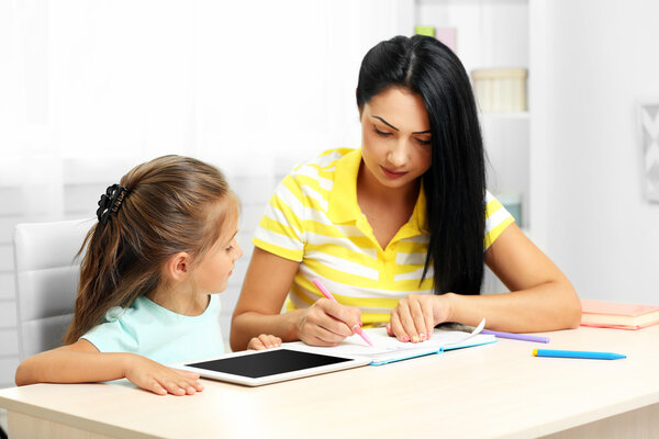 School girl doing homework with mother 