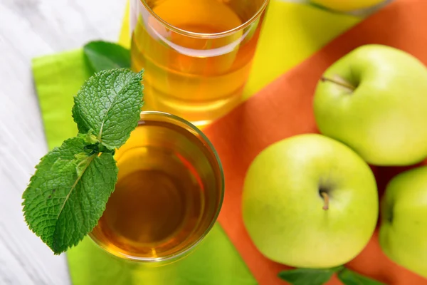 Glasses of apple juice with fruits and fresh mint on table close up — Stock Photo, Image