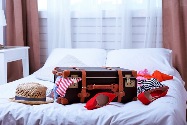 Чемодан с одеждой на кровати в номере
