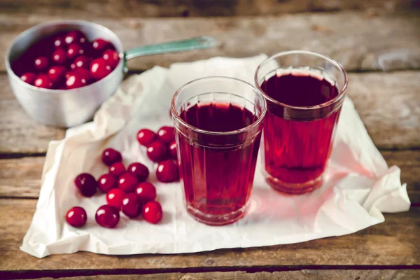 Dvě skleničky s cherry šťáva na stole, na dřevěné pozadí — Stock fotografie