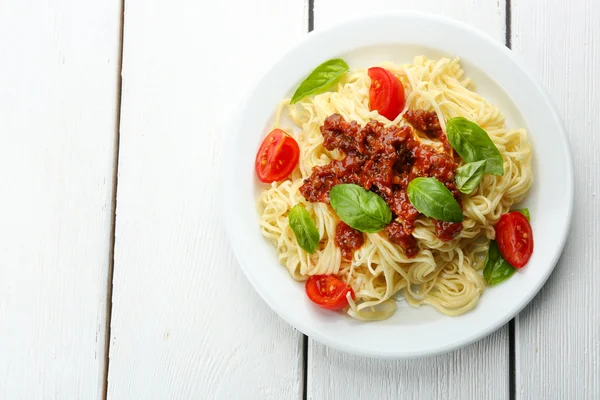 Spaghetti Bolognese on white plate, on color wooden background — Stock Photo, Image