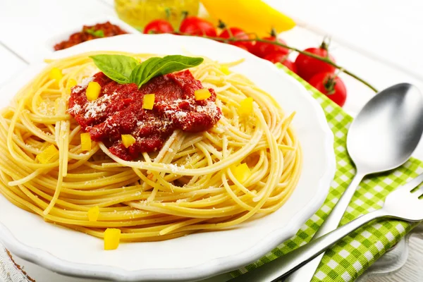 Espaguetis con salsa de tomate y queso en plato blanco, sobre fondo de madera de color — Foto de Stock