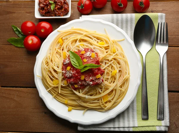 Spaghetti with tomato sauce, paprika and cheese on white plate, on color wooden background — Stock Photo, Image