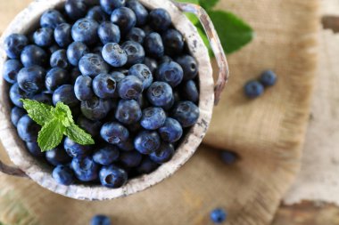 Lezzetli olgun yaban mersini masada kova yeşil yaprakları ile yakın çekim