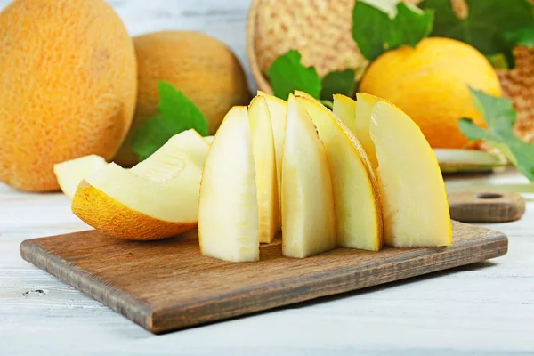 Fatias de melões maduros com folhas verdes na mesa close-up — Fotografia de Stock