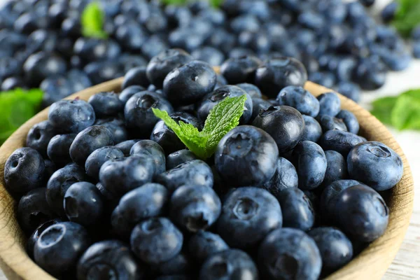 Gustosi mirtilli maturi con menta in ciotola sul tavolo da vicino — Foto Stock