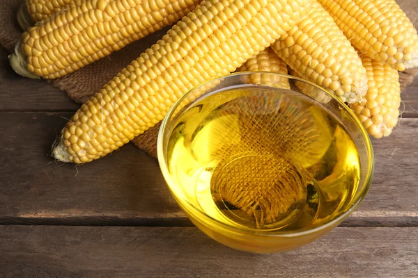 Fresh corn with bowl of oil on table close up — Stock Photo, Image