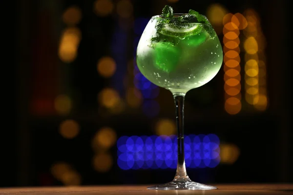 Glass of cocktail on dark blurred lights background — Stock Photo, Image