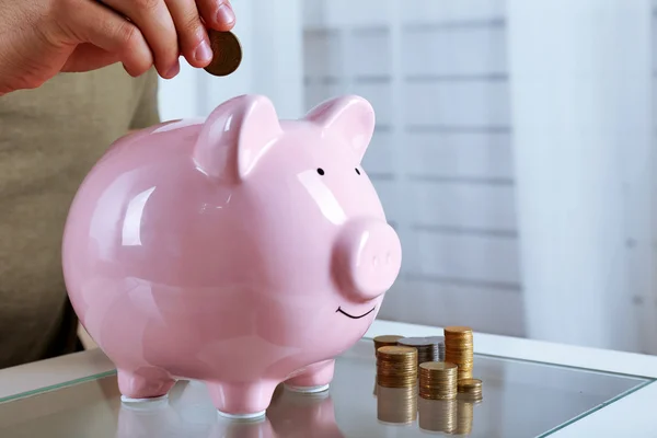 Man puts coin into a piggy-bank — Stock Photo, Image