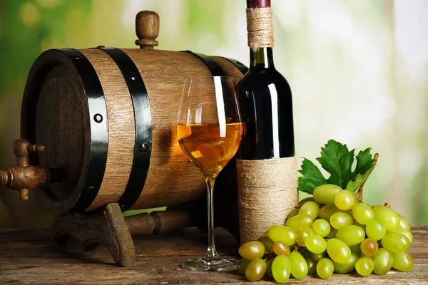 White and red grape with wine bottle near barrel on wooden table, close up — Stock Photo, Image