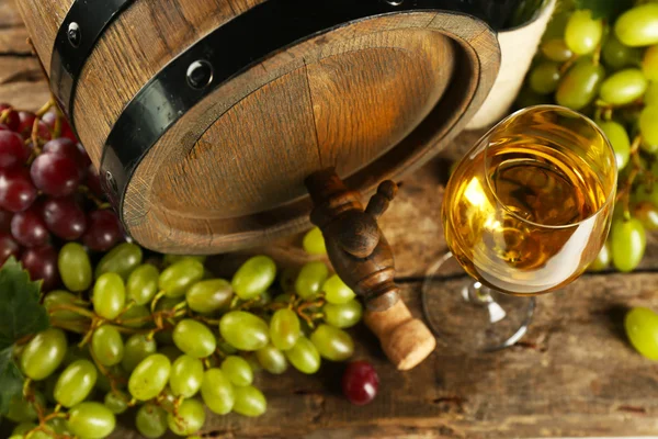 Uva branca e vermelha com garrafa de vinho perto do barril no fundo de madeira — Fotografia de Stock