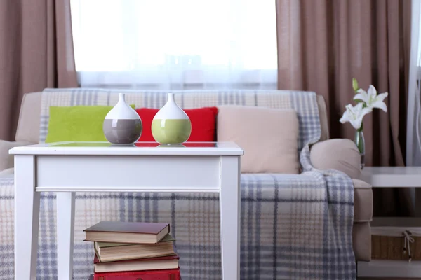 Beige sofa with beautiful pillows and decorative vases on the table in front of it in the room