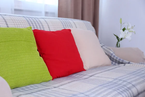 Sofá acolhedor com três travesseiros macios coloridos no quarto — Fotografia de Stock