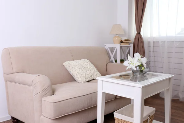 Pastellfarbenes Sofa mit schönen Kissen und Vase mit Blumen auf dem Tisch davor im Zimmer — Stockfoto