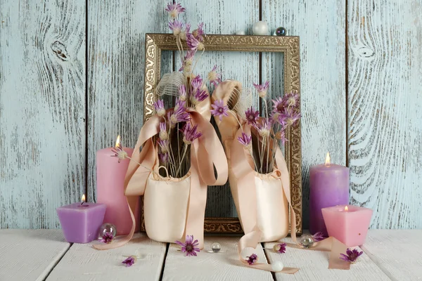 Dekoriert mit Blumen und Kerzen Ballettschuhe im Rahmen auf blauem Holzgrund — Stockfoto