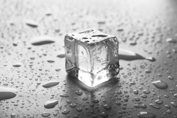 Cubo de hielo de fusión transparente con gotas alrededor, de cerca — Foto de Stock