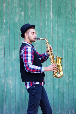 Müzisyen saksafon yeşil ahşap arka plan üzerinde çalış.