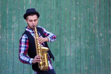 Müzisyen saksafon yeşil ahşap arka plan üzerinde çalış.