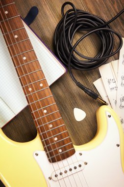Elektro gitar nota ve ahşap arka plan üzerinde kablo ile