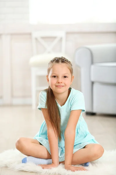 Pequena menina bonito sentado no tapete — Fotografia de Stock