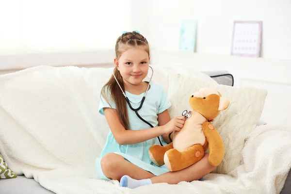 Ragazza con orsacchiotto seduta sul divano — Foto Stock